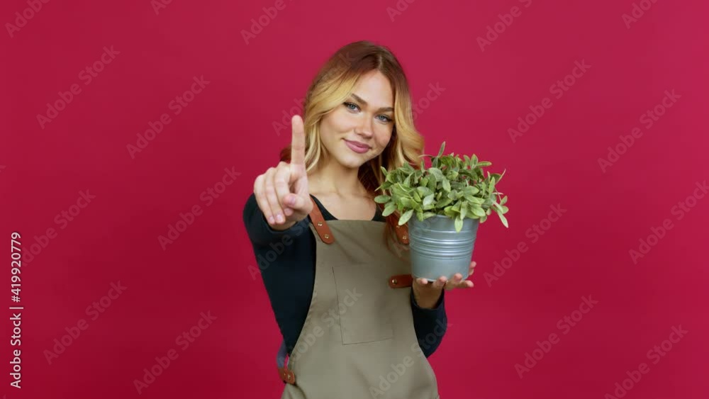 Young blonde girl holding a plant showing and lifting a finger in sign of the best over isolated background Young blonde girl holding a plant showing and lifting a finger in sign of the best over isolated background
