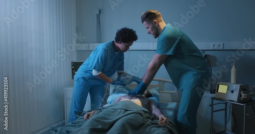 Doctors putting an oxygen mask on patient and doing cardiac massage in hospital.