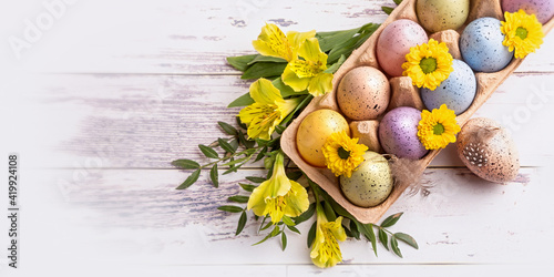 Multicolored Easter eggs in a tray and flowers