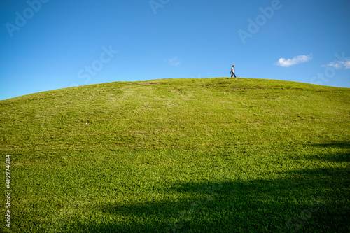 Silhouette of a man peacefully walking on top of a curved lawn hill