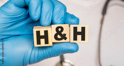 HH Hemoglobin and hematocrit - word from wooden blocks with letters holding by a doctor's hands in medical protective gloves. Medical concept. photo