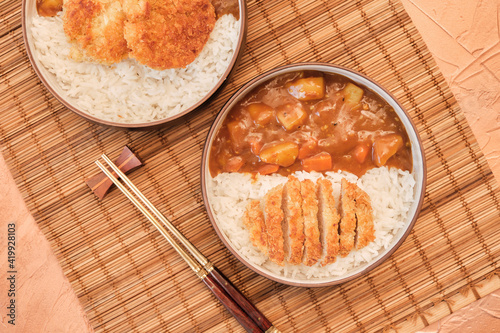 Top view Japanese curry rice topping with fried pork and vegetables in white and black plate with chopsticks. Curry rice Japanese food.
