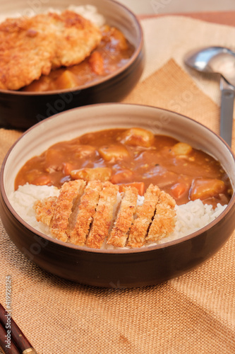 Top view Japanese curry rice topping with fried pork and vegetables in white and black plate with chopsticks. Curry rice Japanese food.