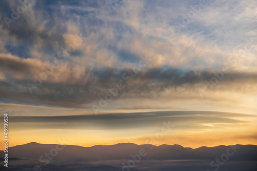 Beautiful panoramic view on the mountains silhouette on the sunset with bright clouds.