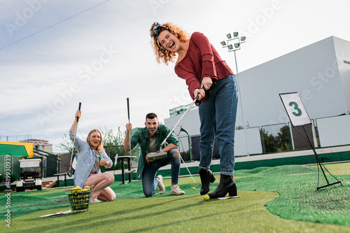 Group of smiling friends enjoying together playing mini golf in the city. © Zoran Zeremski