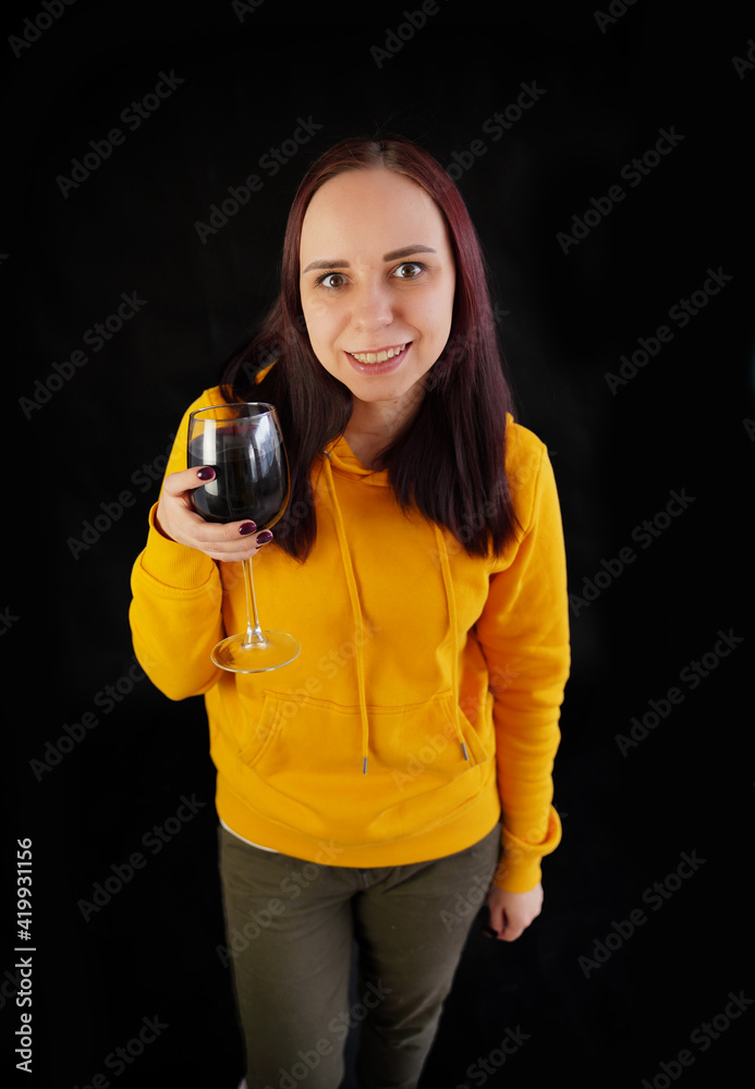 Relaxed young woman poses with glass of red wine on black background. Adult happy brunette resting with alcohol in her weekend. Relaxed young woman poses with glass of red wine on black background. Adult happy brunette resting with alcohol in her weekend.
