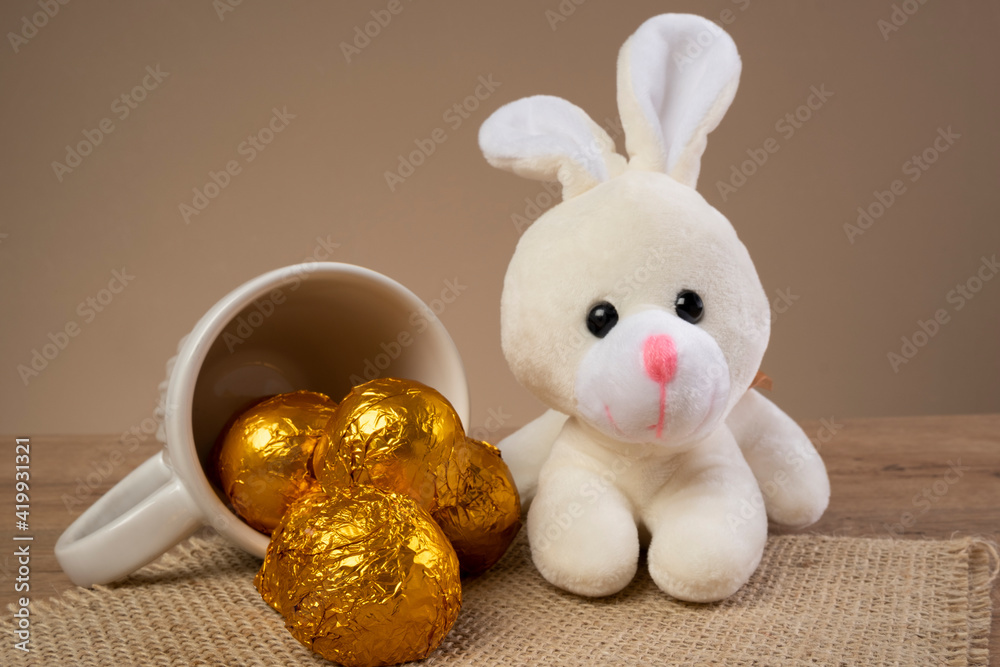 Fototapeta premium chocolate truffles wrapped in golden foil next to Easter ornaments