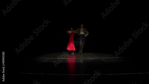Ballroom dance couple show dancing Spanish paso doble element on the dark stage photo