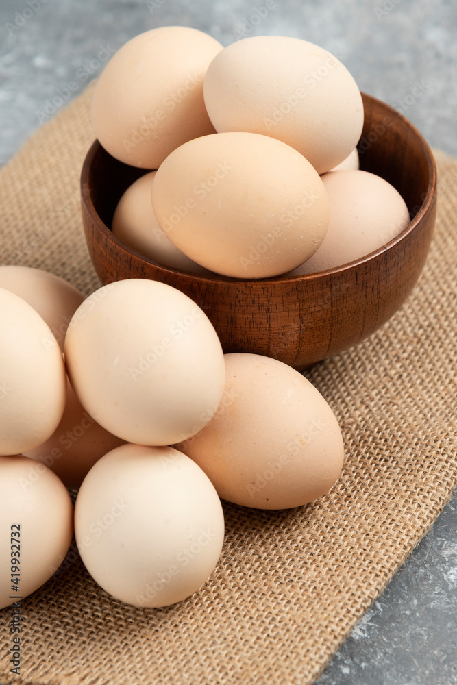 Wooden bowl of organic raw eggs on marble surface Wooden bowl of organic raw eggs on marble surface