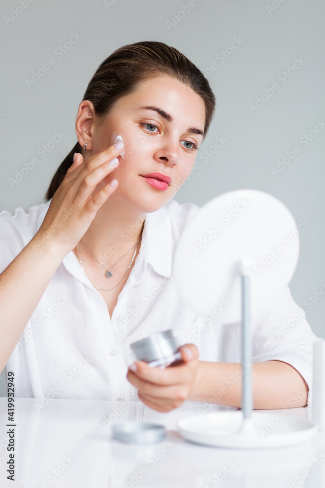Beautiful elegant woman applying cream on face Beautiful elegant woman applying cream on face