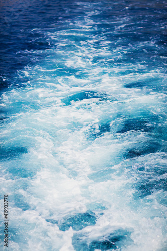 Wave trace tails of speed boat on a blue water surface in the sea