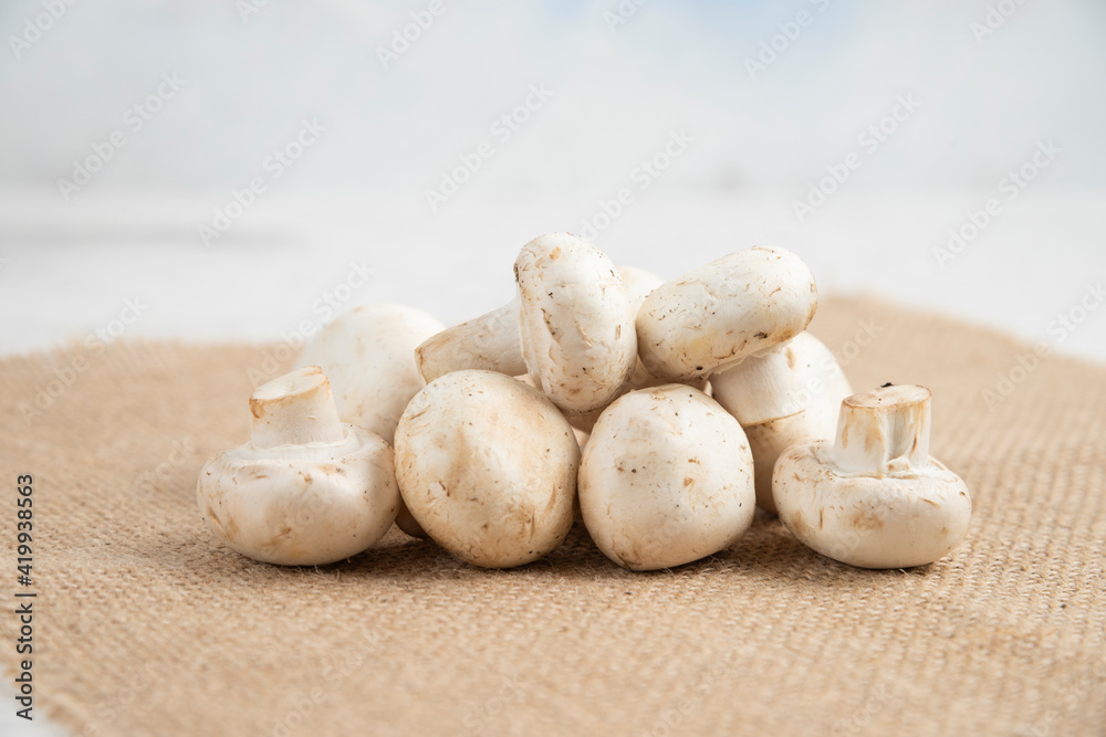 White mushrooms isolated on a piece of burlap White mushrooms isolated on a piece of burlap