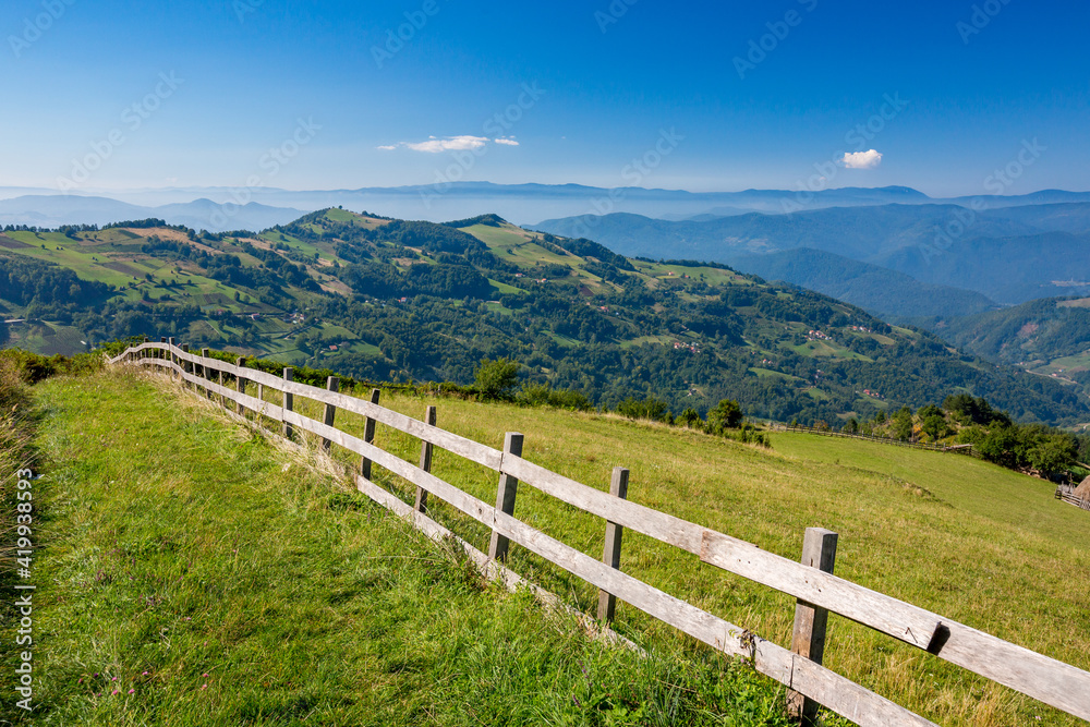 Long wooden fence along a mountain road with a scenery hills landscape, Western Serbia. Bio stock-breeding and farming.