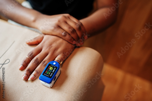African american women with pulse oximeter on hand measuring oxygen saturation level. photo