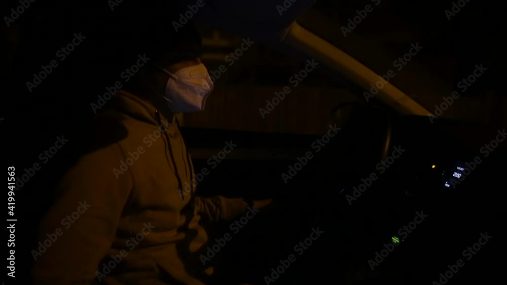 A man wearing a respirator uses a phone in a car in a parking lot. Receiving information from the phone, using the mobile Internet. A man wearing a respirator uses a phone in a car in a parking lot. Receiving information from the phone, using the mobile Internet.