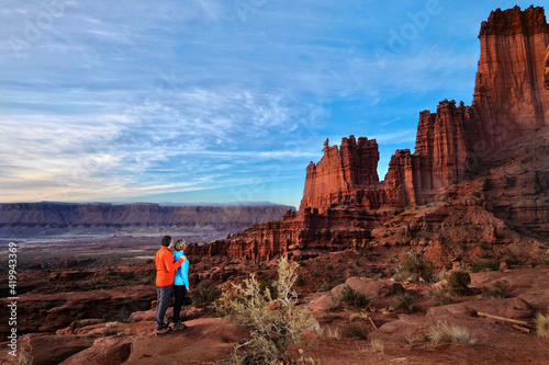Adventurous couple hiking in desert by red sandstone walls. Scenic Fisher Towers near Moab. Utah. USA 
