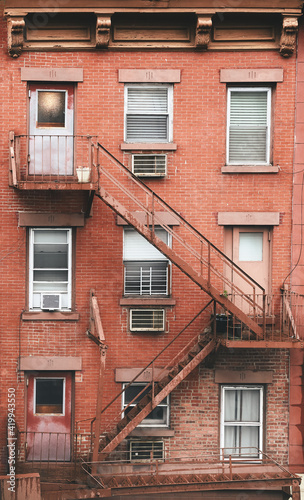 Old brick tenement house with fire escape, New York City, USA.