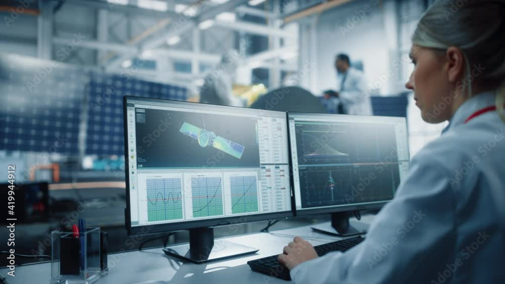 Female Engineer uses Computer to Analyse Satellite, Calculate Orbital Trajectory Tracking. Aerospace Agency International Space Mission: Scientists Working on Spacecraft Construction. Over Shoulder Female Engineer uses Computer to Analyse Satellite, Calculate Orbital Trajectory Tracking. Aerospace Agency International Space Mission: Scientists Working on Spacecraft Construction. Over Shoulder