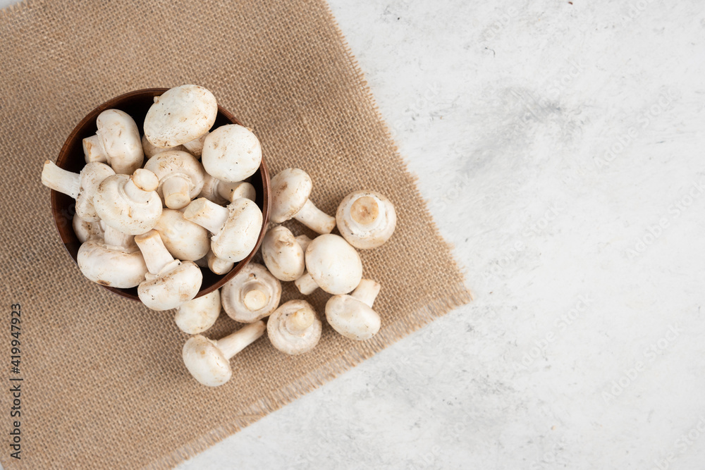 White mushrooms in a wooden cup on a piece of burlap White mushrooms in a wooden cup on a piece of burlap