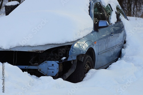 one old blue wrecked car after an accident in a snowdrift of white snow on a winter street