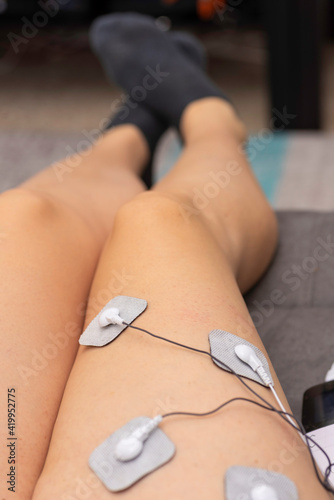 Chica usando un electroestimulador en la pierna.