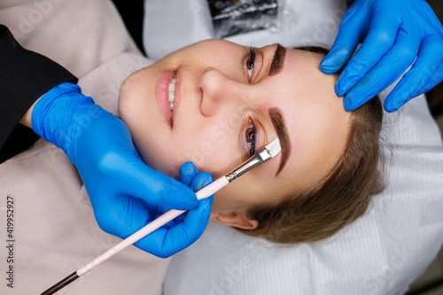 Woman with permanent makeup tattoo on her eyebrows. Close-up beautician makes a sketch of the eyebrows. Professional make-up and cosmetic skin care.