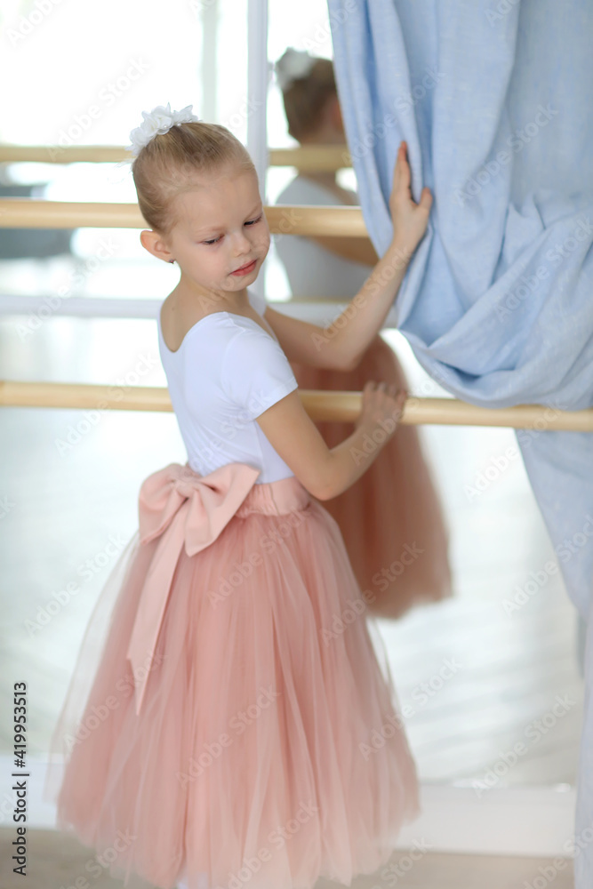 A beautiful ballerina in a pink tutu standing next to a ballet stick . Ballet class. Children and ballet A beautiful ballerina in a pink tutu standing next to a ballet stick . Ballet class. Children and ballet