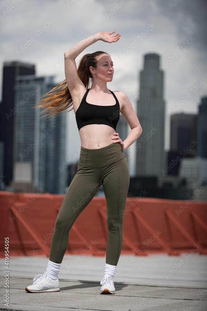 Fototapeta premium Young Athlete Warms Up on Los Angeles Rooftop