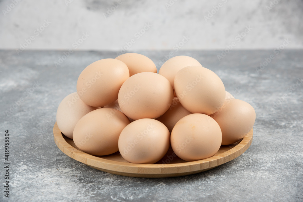 Wooden plate of fresh organic raw eggs on marble surface Wooden plate of fresh organic raw eggs on marble surface