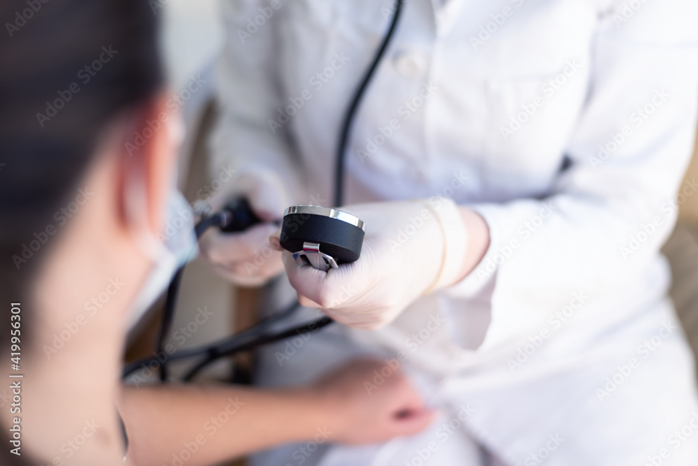 Female doctor using sphygmomanometer with stethoscope checking blood pressure to a patient in the hospital Female doctor using sphygmomanometer with stethoscope checking blood pressure to a patient in the hospital
