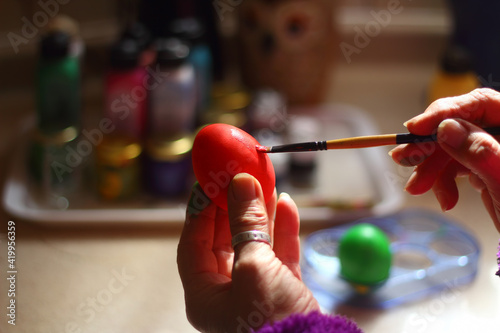 A woman s hand paints an Easter egg. Preparing Easter decorations on Multicolor background. 