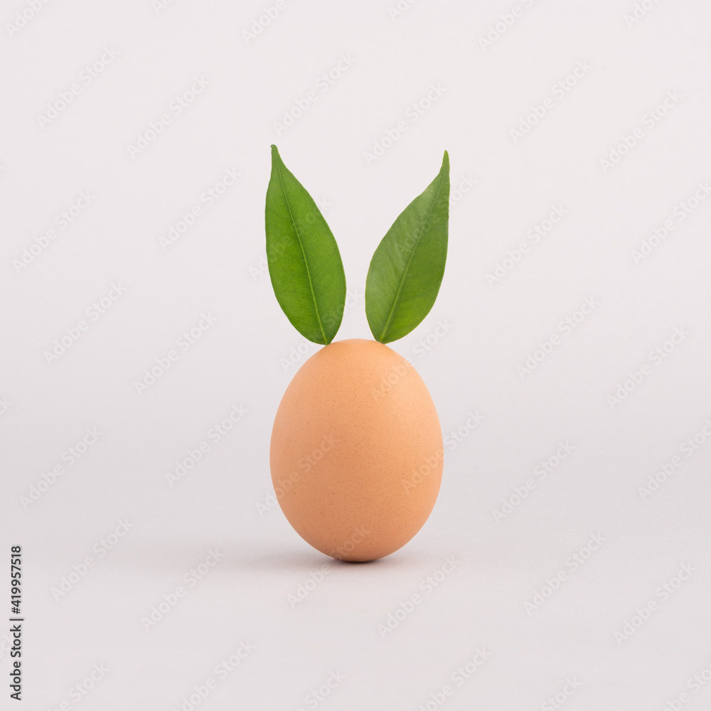 Creative minimal Easter concept with egg and fresh green leaves Creative minimal Easter concept with egg and fresh green leaves