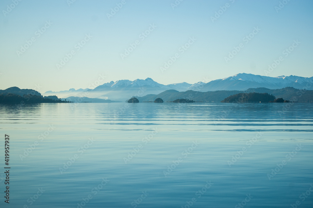 Calma en el lago con las montañas de fondo y la bruma del atardecer. Bariloche, Argentina 