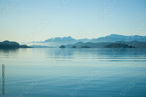 Calma en el lago con las montañas de fondo y la bruma del atardecer. Bariloche, Argentina  © Martin