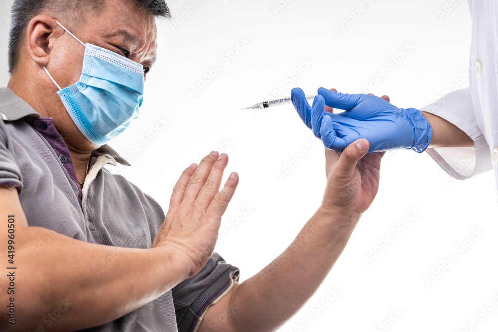 Fearful worried middle age man reacting to medical practitioner holding syringe loaded with Covid-19 vaccine Fearful worried middle age man reacting to medical practitioner holding syringe loaded with Covid-19 vaccine