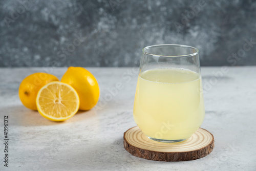 A glass cup of fresh lemon juice on a wooden board