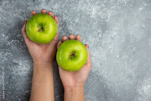 Woman hands holding green apples on marble background