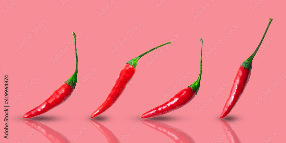 Small hot red chilli peppers arranged in a row on a pink background