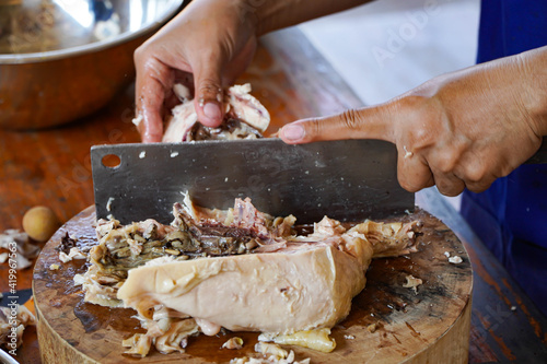 Asian woman's hand is cutting steamed chicken meat.Cooking ideas 