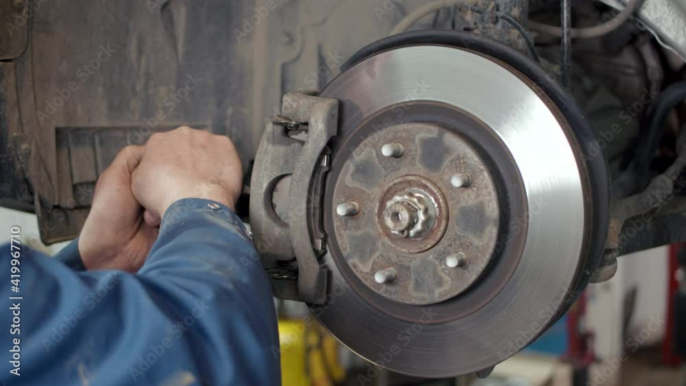Mechanic repairing brake discs in a car vehicle Mechanic repairing brake discs in a car vehicle