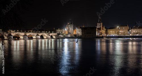 view of the illuminated stone Charles Bridge on the Vltava River in the center of Prague at night