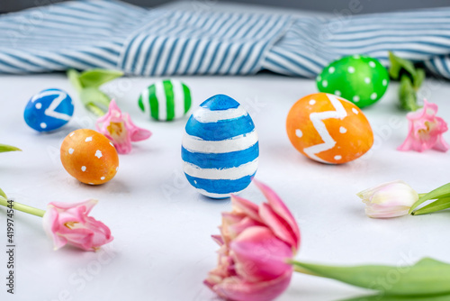 Cute colorful Easter eggs painted with paints and spring flowers tulips on a white background
