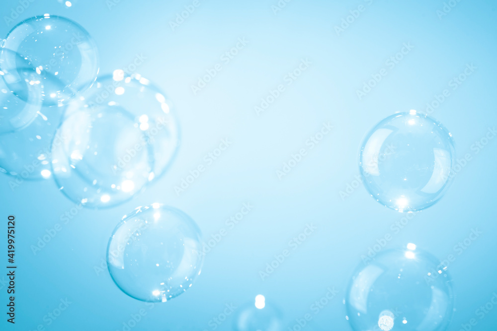 Beautiful shiny transparent soap bubbles floating on a blue background.	