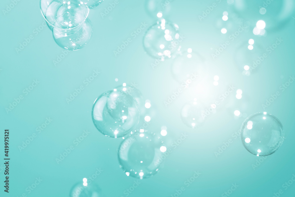 Beautiful shiny transparent soap bubbles floating on a green background.	