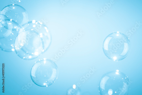 Beautiful shiny transparent soap bubbles floating on a blue background. 