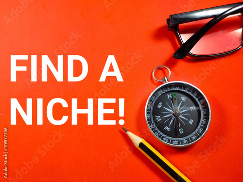 Selective focus.Glasses,pencil and compass with text FIND A NICHE on red background.Business concept.