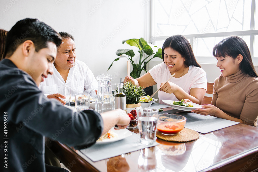 latin family, daughter eating salad together at home in Mexico city latin family, daughter eating salad together at home in Mexico city