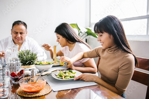 latin family and daughter eating salad together at home in Mexico city