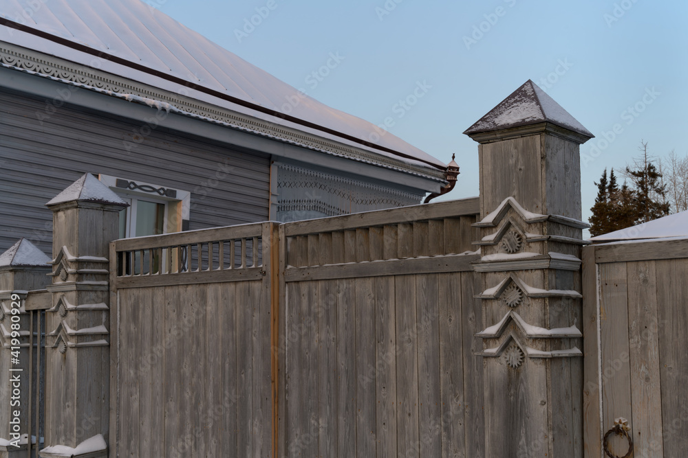 Details of finishing a wooden fence with carved pillars in the provincial city of Tobolsk (Siberia, Russia) on a frosty winter morning. Lots of architectural details and beautiful decorations 