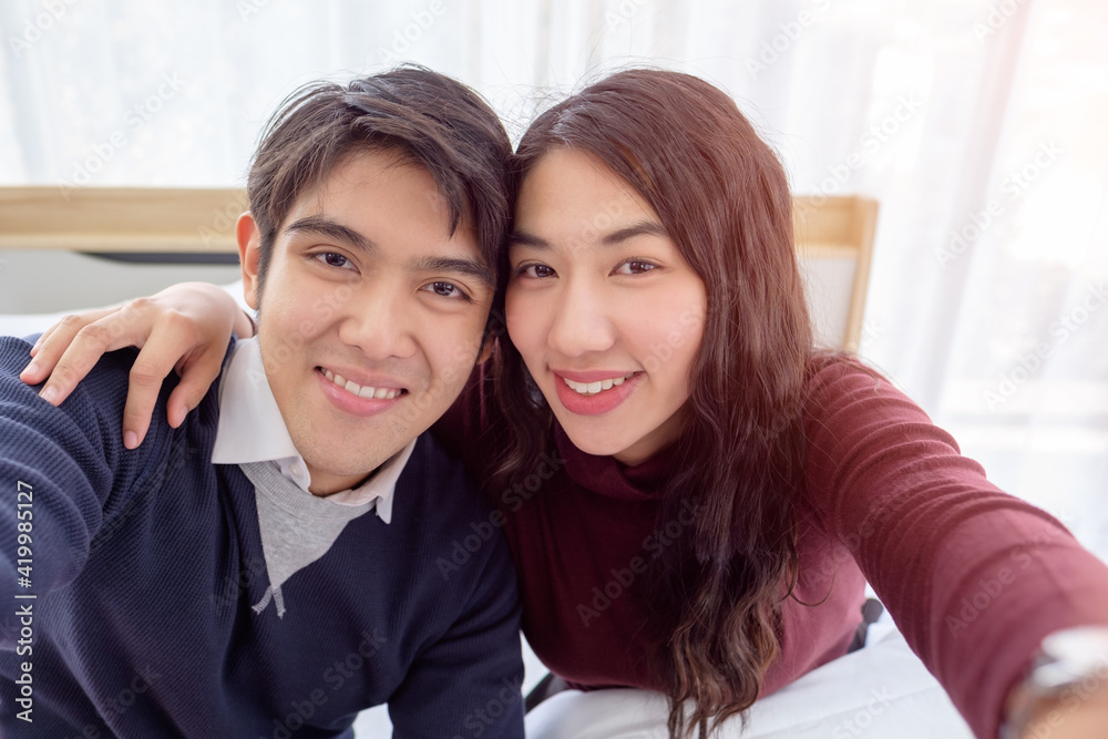 Smiling young asian couple on white bed, Valentine's day and happiness concept. Smiling young asian couple on white bed, Valentine's day and happiness concept.